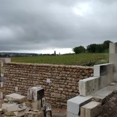 Mur en moellons avec ouverture pour porte et mur d'enceinte en cours de montage