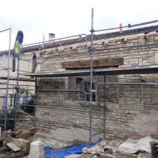 Construction en cours d'un appentis en moellons avec échafaudage
