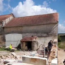 Ouvrier en cours de réalisation d'n mur de moellons