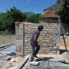 Restauration en cours d'un mur de clôture en moellons