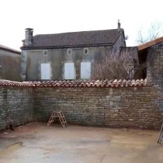 Un mur de clôture en moellons avec couronnement chaperon en tuiles canal