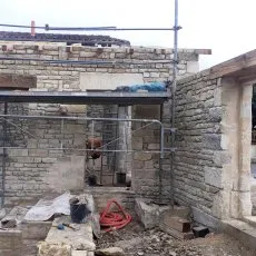 Construction en cours d'un appentis en moellons avec échafaudage