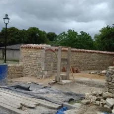 Restauration en cours d'un mur de clôture en moellons